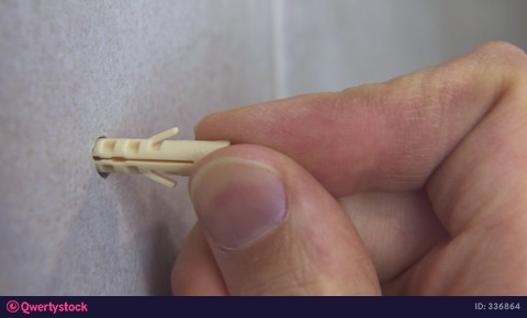 worker's hand inserts a plastic dowel pin into a drilled hole video 336864